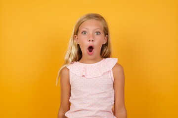 Beautiful Caucasian young girl standing against yellow background, inviting you to come, confident and smiling making a gesture with hand, being positive and friendly.