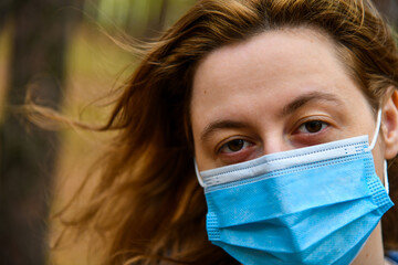 Young woman wearing in a protective mask in a park. Quarantine, anti coronavirus, virus and flu...