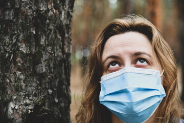 Young woman wearing in a protective mask in a park. Quarantine, anti coronavirus, virus and flu...
