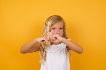 Beautiful Caucasian young girl standing against yellow background has rejection angry expression...