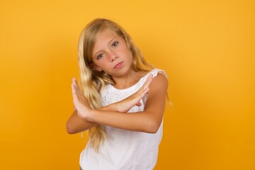 Beautiful Caucasian young girl standing against yellow background Has rejection angry expression on face and crossing hands doing refusal negative sign.