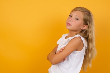 Image of cheerful Beautiful Caucasian young girl standing against yellow background with arms crossed. Looking and smiling at the camera. Confidence concept.