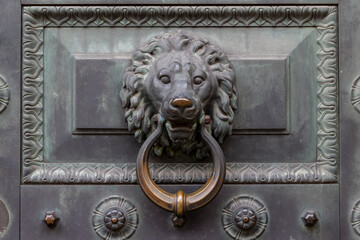 Antique bronze door knocking knob ring in the form of a lion's face on an old door.