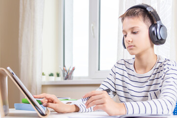 Online learning, remote education, distance lessons at home. Child with digital tablet computer sitting at desk with books and having video call, virtual online leasson, making homework at home.