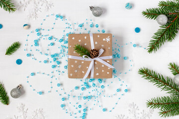 Christmas gift wrapped into eco-paper on the blue garland next to spruce twigs.