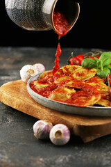 Ravioli with tomato sauce and basil on rustic background