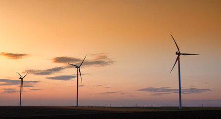 Obraz premium Wind turbine silhouette on colorful sunset landscape 