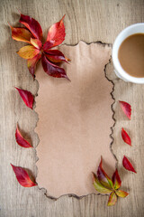 Autumn leaves, a coffee and a note on a light old wooden background with empty space for text. The view from the top. Flat lay