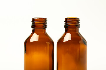 Glass containers for medicines on a white background. Two empty brown pharmaceutical bottles without labels