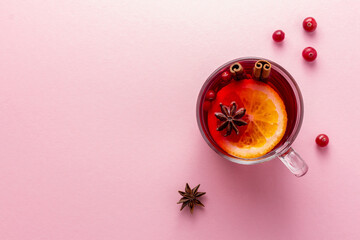 A glass cup of christmas mulled wine or glogg on pink background with copy space