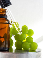 Grape seed oil in a glass bottle with ripe green grape