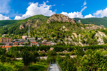 Fototapeta na wymiar The panoramic view of the old center of a French medieval village Puget-Theniers in the low Alps and a metal bridge leading there (Alpes-Maritimes, France)
