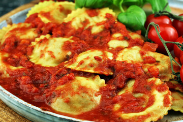 Ravioli with tomato sauce and basil on rustic background
