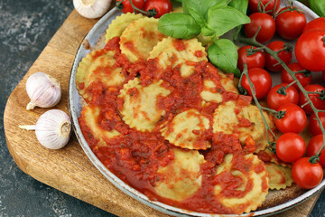 Ravioli with tomato sauce and basil on rustic background