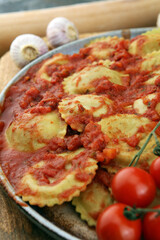 Ravioli with tomato sauce and basil on rustic background