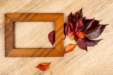 Empty photo frame and colorful autumn dry leaves on wooden background. 