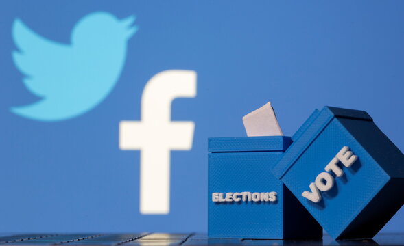3D printed ballot boxes are seen in front of Facebook and Twitter logos