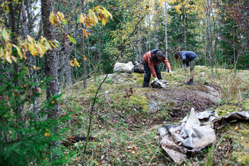 big amount of trash in forest, family father and son picking garbage away, global environment issues