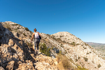 Woman trekking along a path in the natural park of Peñon de Ifach in Calpe, wearing sportswear