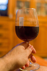 White wine glass on wooden surface with man's hand