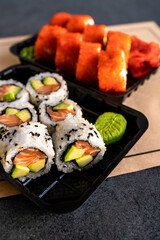 Delivery of Japanese traditional food. Salmon and avocado rolls with black and white sesame seeds in a plastic container