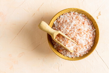 Pink Himalayan rock salt in a bowl and spoon on a light background. Top view, place for text.
