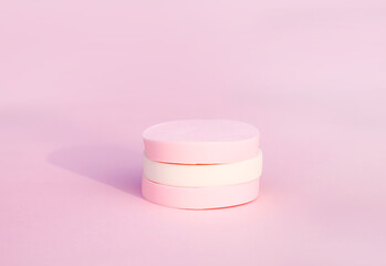 Cosmetic sponges in pastel colors on pink background.