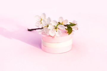 Cosmetic sponges and tree branch with spring flowers on pink background.
