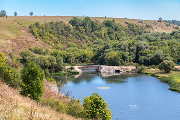 Fototapeta premium View of the Dam on the Vorgol river in the former estate of merchant Taldykin and the high bank of the river near the city of Yelets, Lipetsk region, Russia