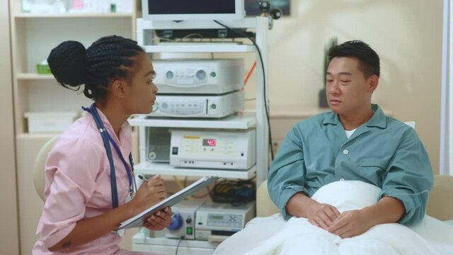 Black attractive smart female doctor consulting male patient in hte hospital. Unhealthy adult man telling symptoms of illness or recovery. Clinic, medicare and health concept.