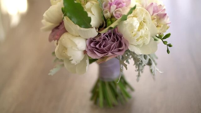 bridal bouquet of white peonies, purple roses, freesia, artemisia and laurel