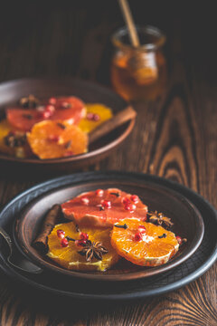Orange dessert with wine honey or maple syrup and ginger spice, decorated pomegranate berries. Wonderfully sweet, rich and fresh food. Dark rustic background, copy space for you text