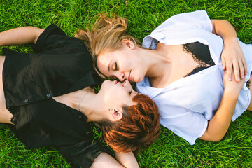 Girls couple in love lying on the grass in a park on a sunny day.