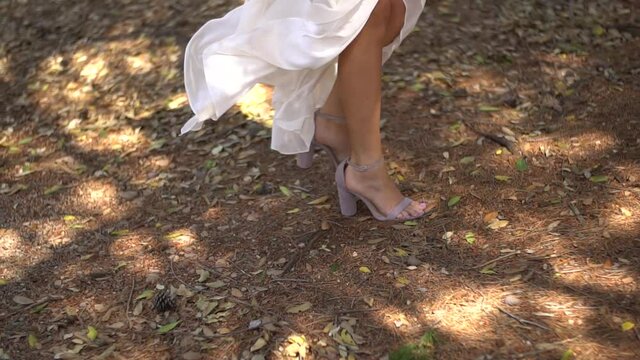 graceful legs of the bride in sandals, fluttering skirt of the wedding dress