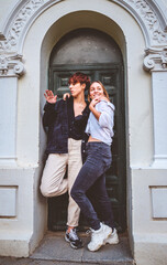 Girls couple standing posing in a dark green door on the street.