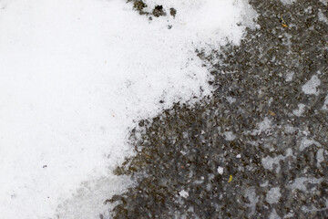 Abstract background. Blue ice with air bubbles and white snow, frozen lake or puddle water surface on cold winter day.