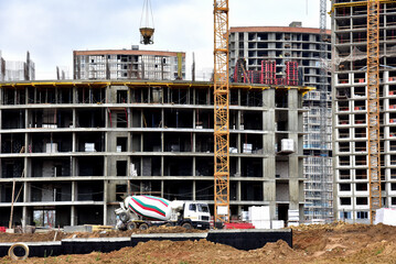 Cement  mixer truck working pouring mix into crane concrete bucket. View of larger construction...