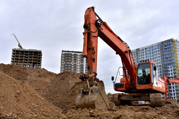 View of a large construction site where earthmoving equipment. Excavator digs the ground to lay...