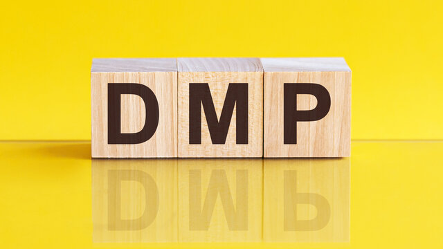 DMP - Data Management Platform - word is made of wooden building blocks lying on the yellow table