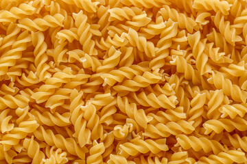 Dry pasta fusilli. Fusilli have spiral shape and yellow color. Pasta is delicious Italian traditional food made from wheat flour like noodles.Pasta background.Top view