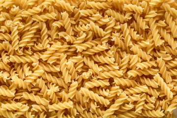 Dry pasta fusilli. Fusilli have spiral shape and yellow color. Pasta is delicious Italian traditional food made from wheat flour like noodles.Pasta background.Top view