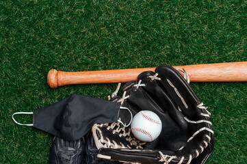 Baseball bat, ball, glove and mask isolated on a field of grass. Baseball season with face mask. Safe sport concept