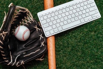 Baseball bat, ball, glove and computer keyboard isolated on a field of grass. Flat lay, top view. Sport home and workout online concept