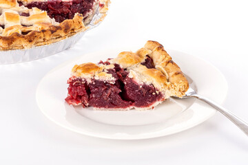 A Slice of Cooked Cherry Pie on a White Porcelain Plate with a Fork Isolated on White Background