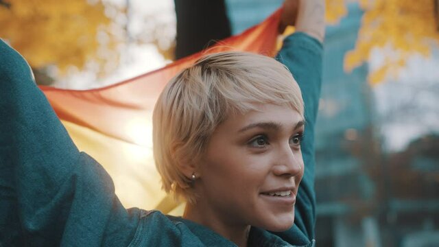 beutiful young woman with short hair lifing rainbow flag from her head in the air. High quality 4k footage