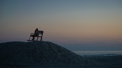 silhouette of lifeguard at dusk on ocean beach