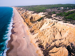 Aerial view of waves on a beautiful sandy ocean beach and cliff