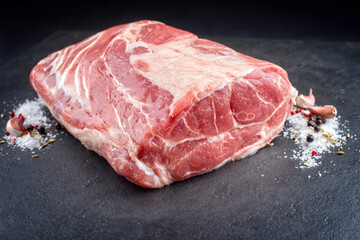 Traditional raw corned pot pork roast with garlic and spice offered as close-up on a black