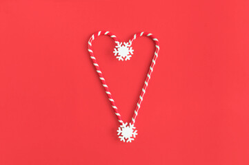 Two Christmas red and white heart shaped lollipops on a red paper background. View from above. Flat lay