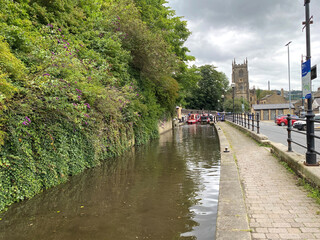 The Rochdale canal, with boats, and a tower clock in the distance in, Sowerby Bridge, Halifax, UK